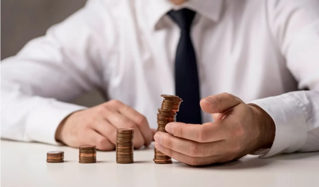 Man in a shirt and tie stacking coins on a table